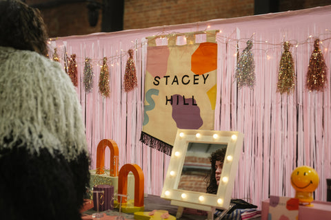 Wedding show booth with jewelry maker's display featuring hanging banner and table jewelry.