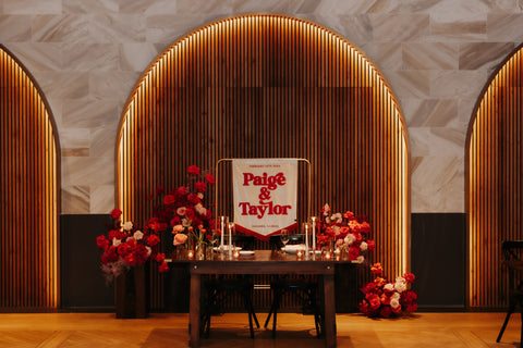 A modern wedding venue with wooden paneling, floral decorations, and a velvet wedding banner.