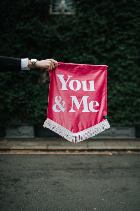 Velvet wedding banner in pink with "you and me" text, held by groom.