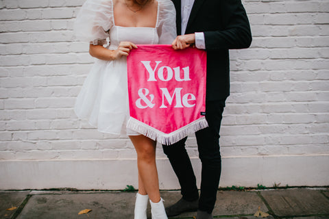 Velvet wedding banner in pink with "you and me" text, held by married couple