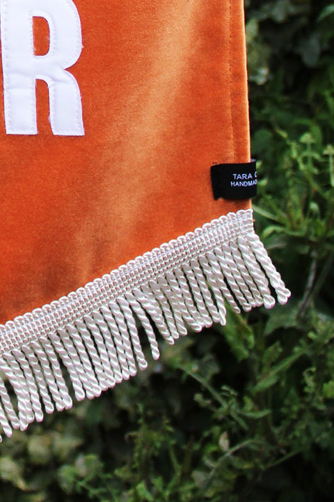 Velvet wedding banner in orange with details of white fringing.