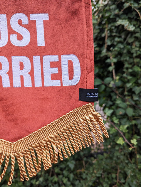 Velvet banner in terracotta with "just married" text on ivy leaf background.