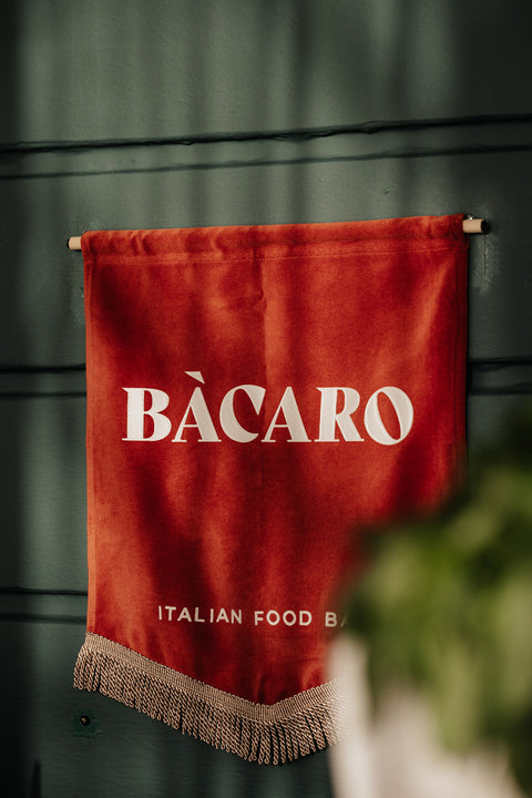 Restaurant signage banner in terracotta with "Bacaro" brand lettering in cream.