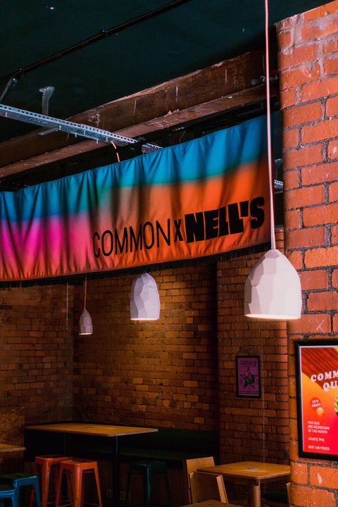 Horizontal banner with "Common x Nell's" text on colourful gradient cotton