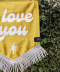 Velvet wedding banner in gold with "i love you" text, white fringing and white star applique on ivy leaf background.