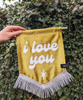 Velvet wedding banner in gold with "i love you" text on ivy leaf background.