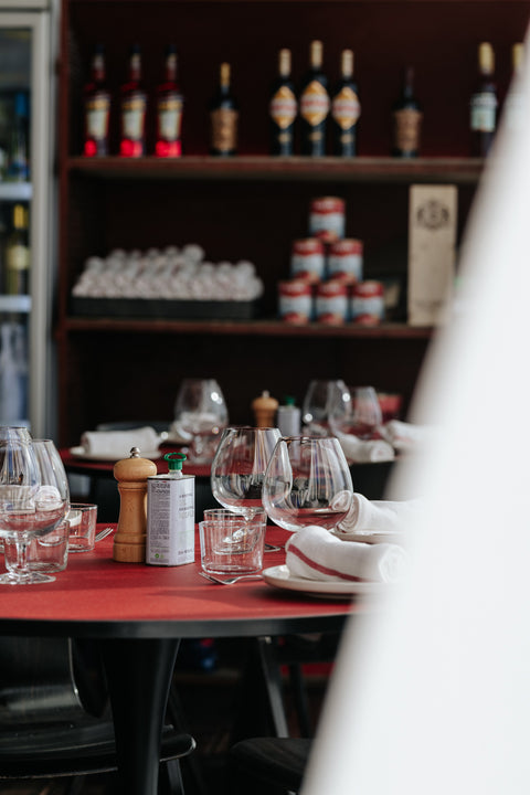 Inside an Italian restaurant: wine glasses, salt and pepper on table setting.