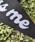 Felt pennant banner in black and white with "kiss me" text with white stitching on ivy leaf background.