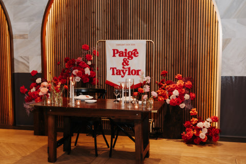 Elegant wedding banner on wooden backdrop with flower accents.
