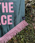 Velvet wedding banner in green with "this must be the place" pink text and pink fringing on ivy leaf background.