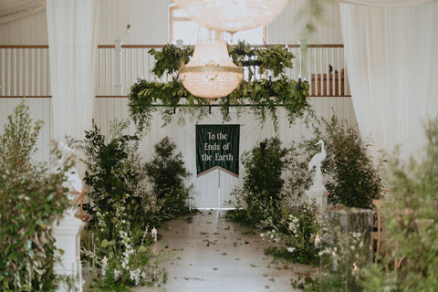 Wedding banner with "to the ends of the earth" text shown in venue at event.
