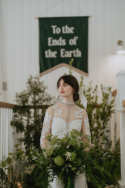 Velvet wedding banner in green with "to the ends of the earth" text behind bride at event.