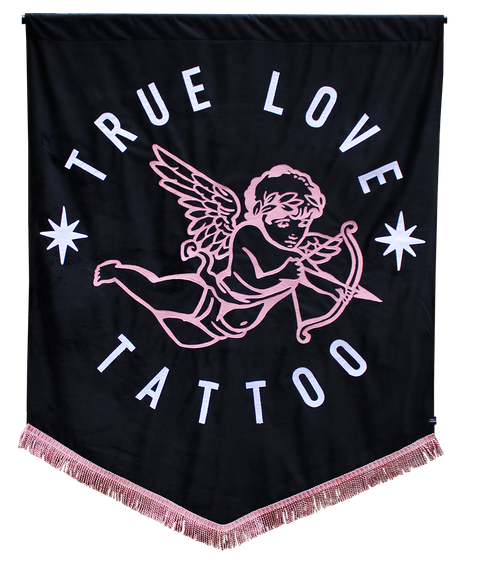 Black banner with name of business "true love tattoo" text, with angel detailed applique and pink fringing.