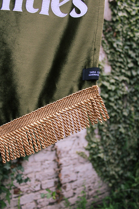 Close up of velvet wedding banner in green with gold fringing.