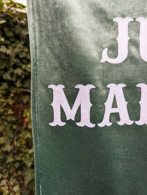 Super close up of velvet wedding banner in green showing stitching detail.