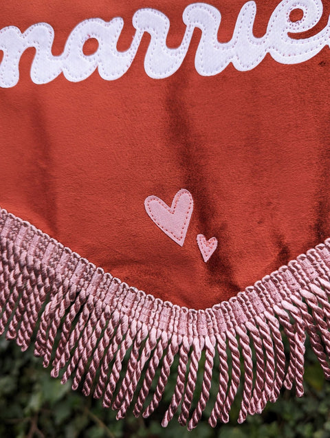 Velvet banner in terracotta showing close up of pink fringing and pink heart appliques.