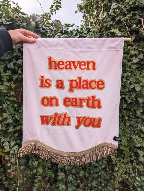 Baby pink velvet banner with of red "heaven is a place on earth with you" text outlined in shiny gold.