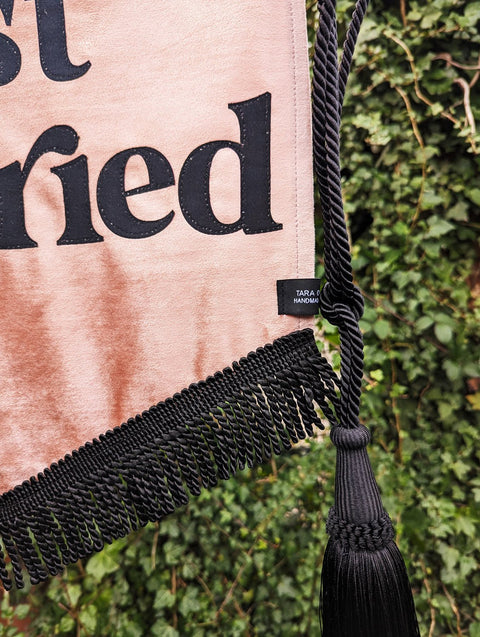 Velvet banner in dusty pink with "just married" text, black fringing and black hanging tassel.