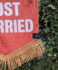 Velvet banner in terracotta with "just married" text on ivy leaf background.