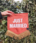 Velvet banner in terracotta with "just married" text on ivy leaf background.
