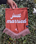 Velvet banner in terracotta with "just married" text with pink fringing on ivy leaf background.
