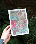 Hand holding A5 risograph print of pomponette flowers.